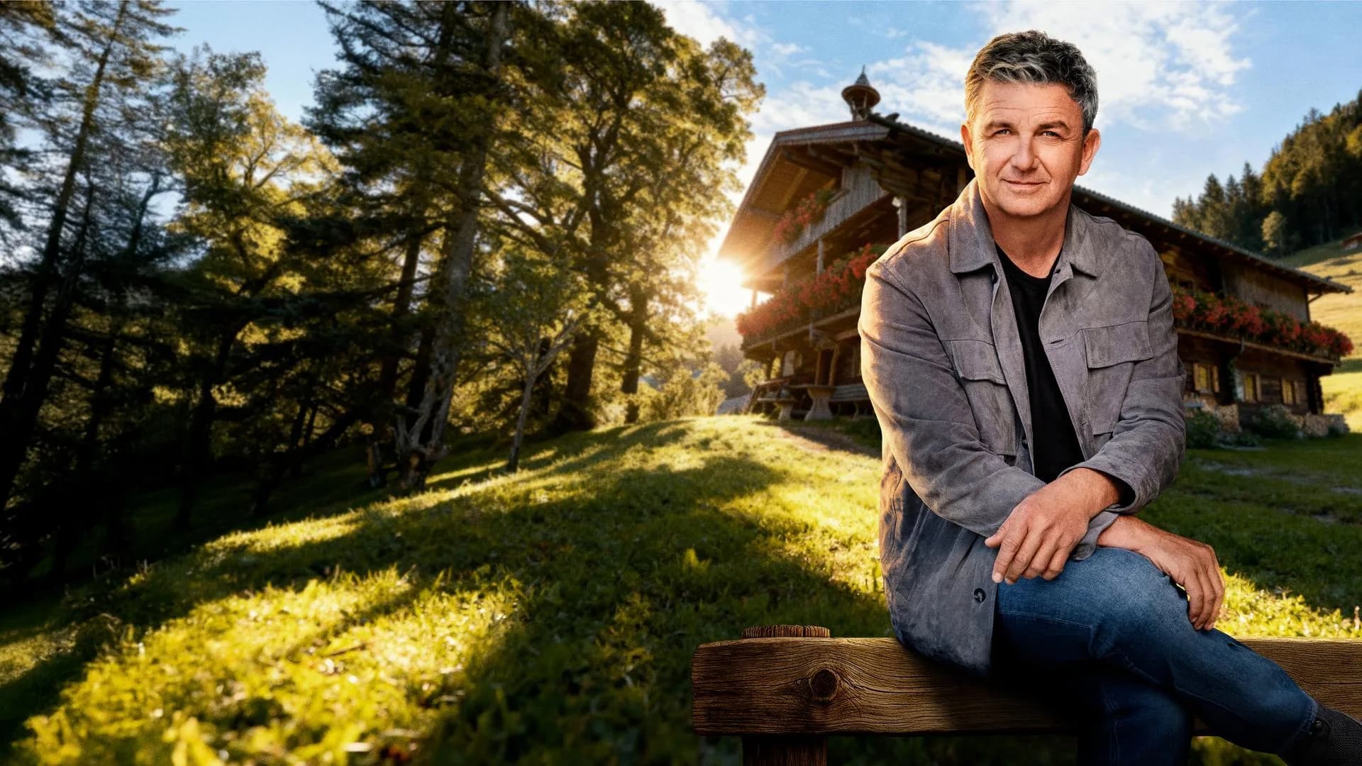 Hans Sigl Bergdoktor: Hans Sigl als Dr. Martin Gruber sitzt auf einer Holzbank vor einem Tiroler Bauernhof am Wilden Kaiser