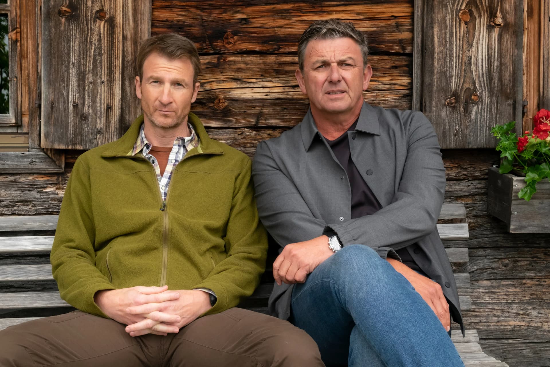 Hans Gruber (Heiko Ruprecht) und Martin Gruber (Hans Sigl) sitzen nachdenklich nebeneinander auf der Bank, Der Bergdoktor Staffel 20