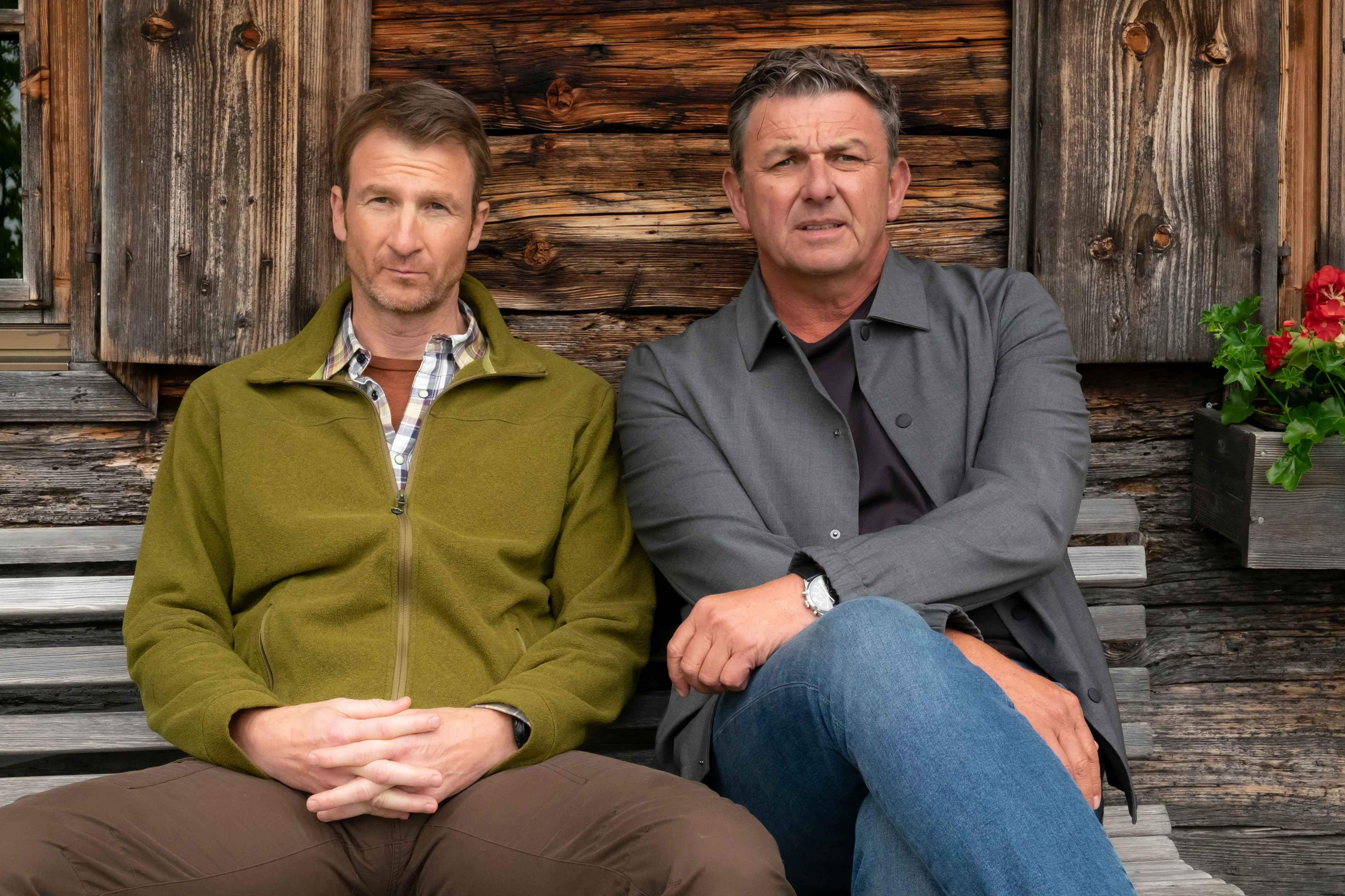 Hans Gruber (Heiko Ruprecht) und Martin Gruber (Hans Sigl) sitzen nachdenklich nebeneinander auf der Bank, Der Bergdoktor Staffel 20